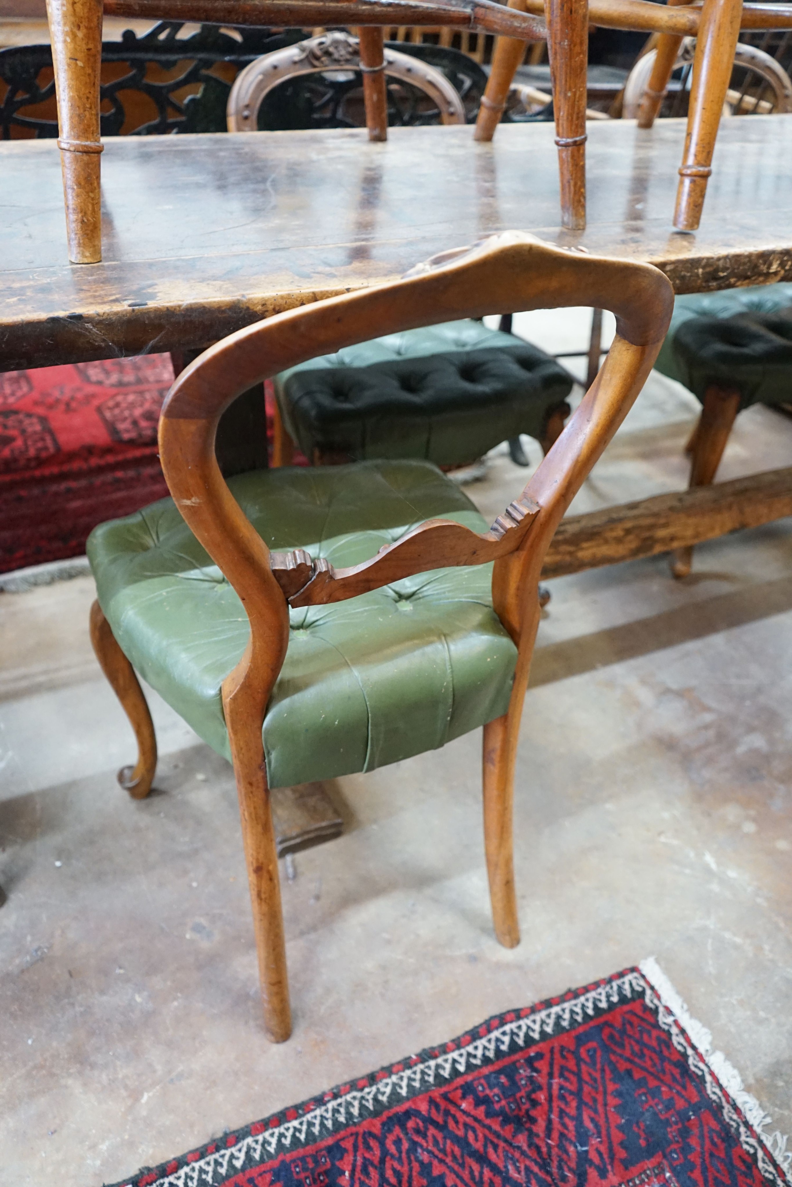 A set of six Victorian carved walnut and buttoned green leather spoon back dining chairs